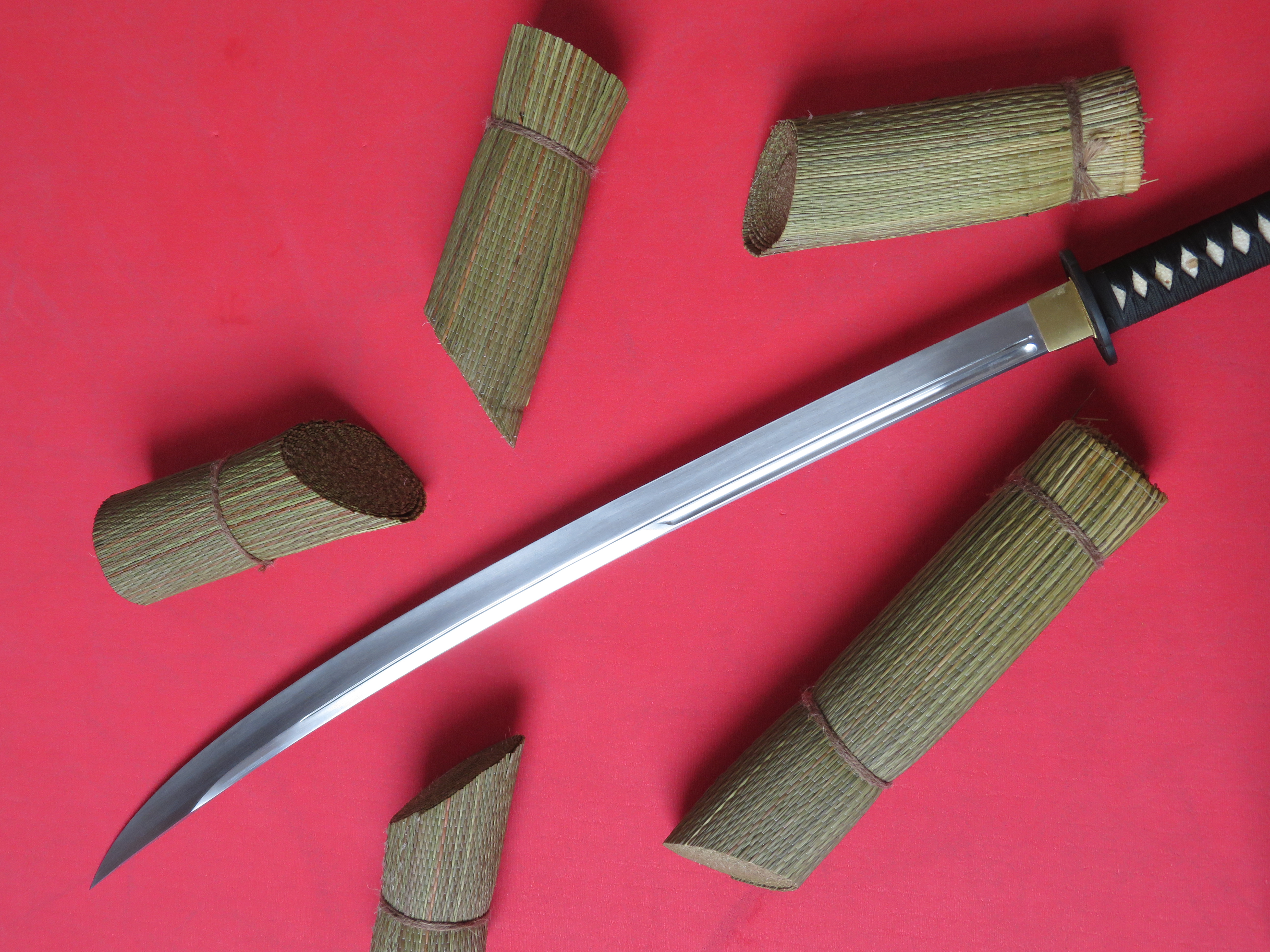 Nasekané smotané namočené rohože tatami omote a čepel meče nodachi od firmy Cold Steel.